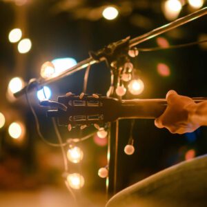Rear view of the man sitting play acoustic guitar on the outdoor concert with a microphone stand in the front, musical concept.